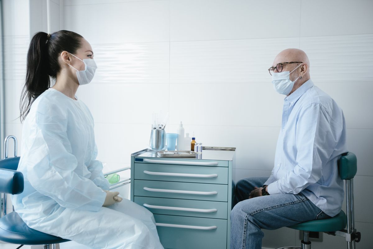 Adult man and healthcare professional seated for a conversation in a clinic.