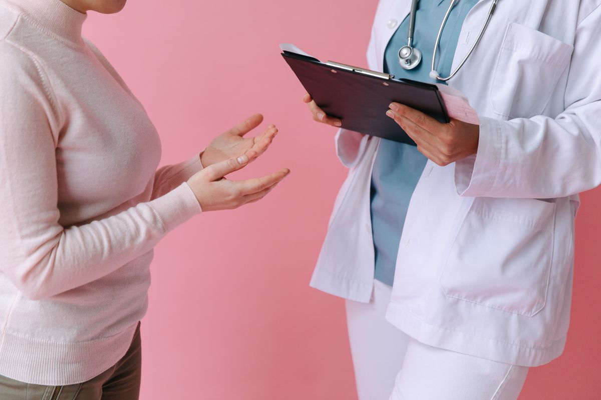 Two adults in conversation, with a healthcare professional holding a clipboard.