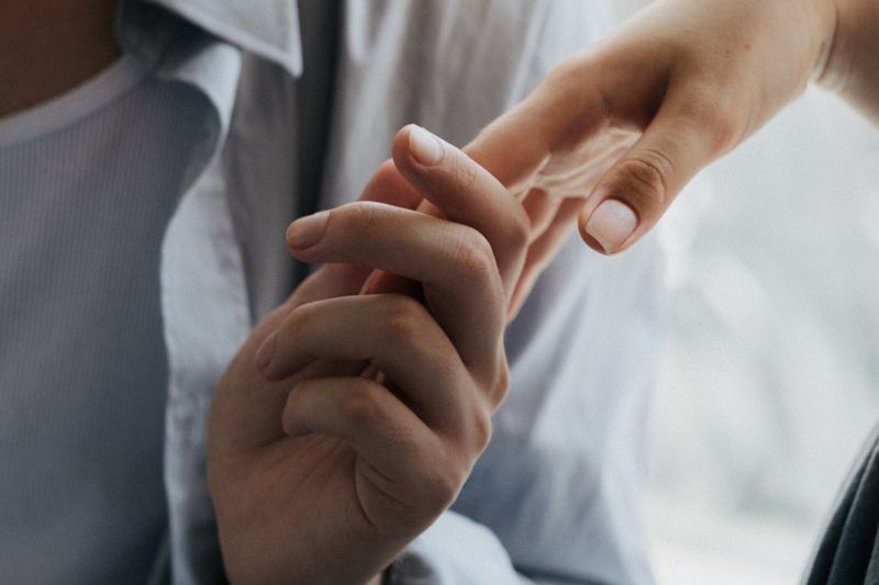 Close-up of two adults gently holding hands.