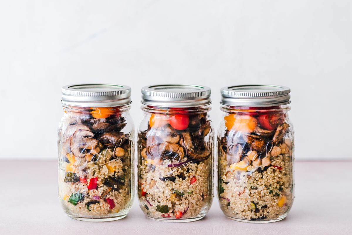 Three glass jars filled with quinoa, chickpeas and colorful vegetables.